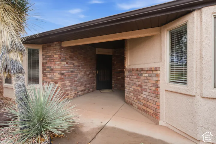 Covered entryway featuring a brick facade, stucco siding, and multi-paned windows