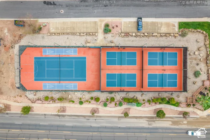 Recreational facility featuring a full-size tennis court with integrated shuffleboard, four dedicated pickleball courts, perimeter fencing, and desert landscaping