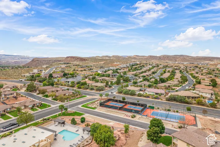 Aerial perspective featuring a community swimming pool, multi-court tennis facility, and mountain backdrop