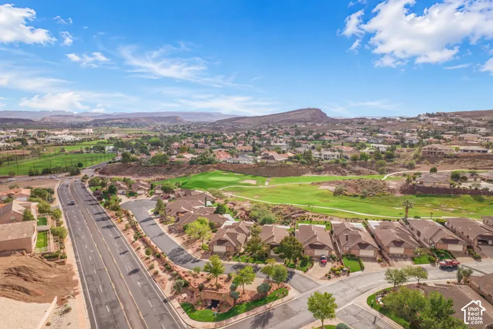 Aerial perspective of a suburban neighborhood featuring paved streets, multi-car garages, desert landscaping, and mountain backdrops