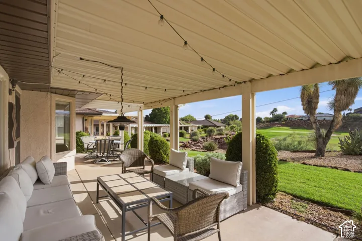 Covered patio featuring concrete flooring, a metal roof structure, and a lawn with mature landscaping