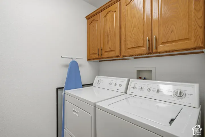 Laundry area featuring overhead wood-finish cabinetry with brushed-finish hardware and a recessed utility box