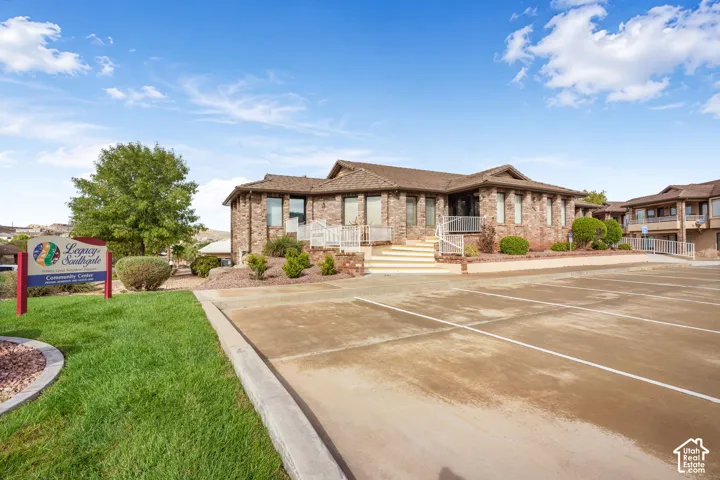 Brick exterior community building featuring concrete parking, tiered stair access, metal railings, and landscaped grounds