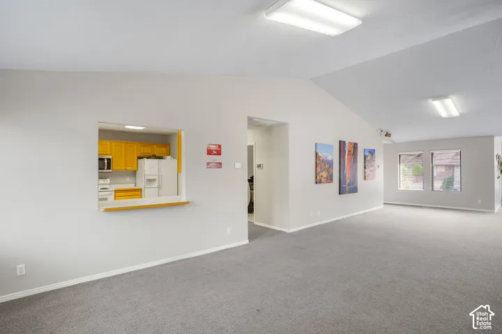 Vaulted ceilings, carpeting, dual-pane windows, and a pass-through kitchen opening with a built-in counter