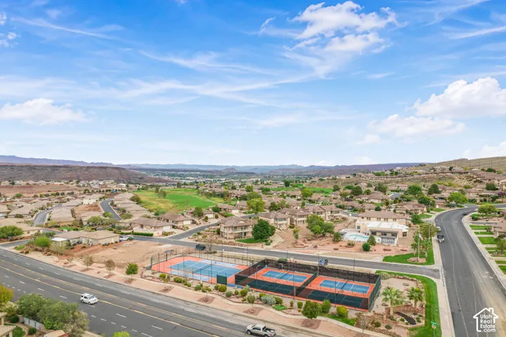 Aerial view of the property grounds featuring three tennis courts, a swimming pool, and desert mountain backdrop