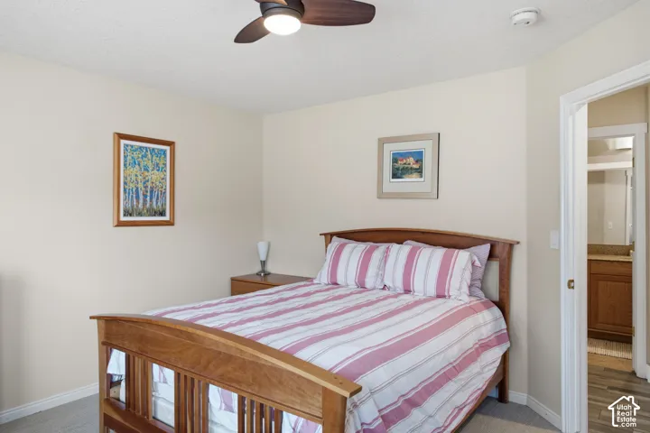 Bedroom featuring neutral wall paint, overhead ceiling fan with light fixture, carpeted flooring, and doorway access to an additional room