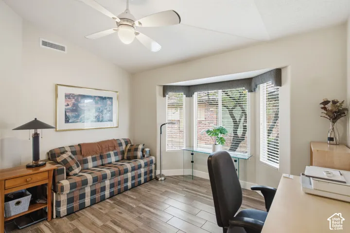 Room featuring vaulted ceilings, wood-finish flooring, and a bay window