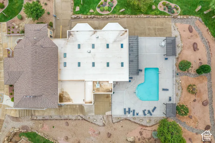 Aerial perspective featuring a tile-roofed structure, multiple roof skylights, a concrete pool deck, a swimming pool, and pergola shading