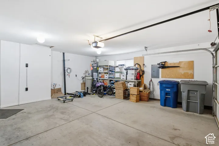 Multi-car garage featuring a concrete floor, automated overhead garage door opener, and water heater