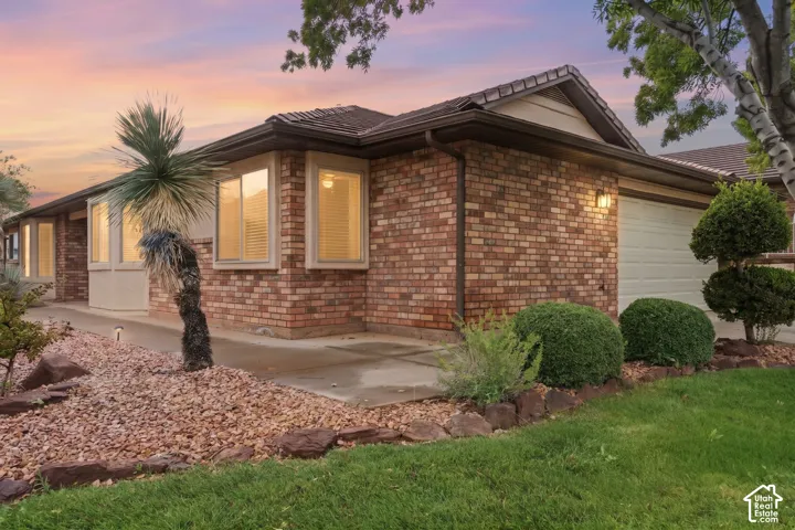 Single-story brick exterior featuring a low-pitch roofline, attached two-car garage, bay windows, and drought-tolerant landscaping with decorative rock beds