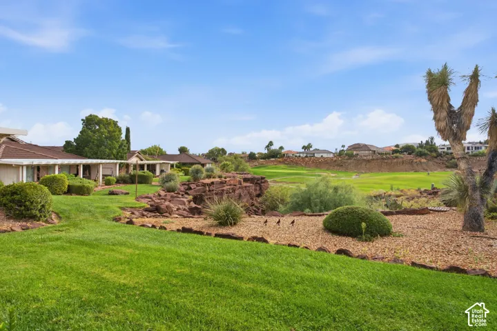 Expansive rear grounds featuring a terraced rock formation, manicured lawn, xeriscaping, and mature native trees