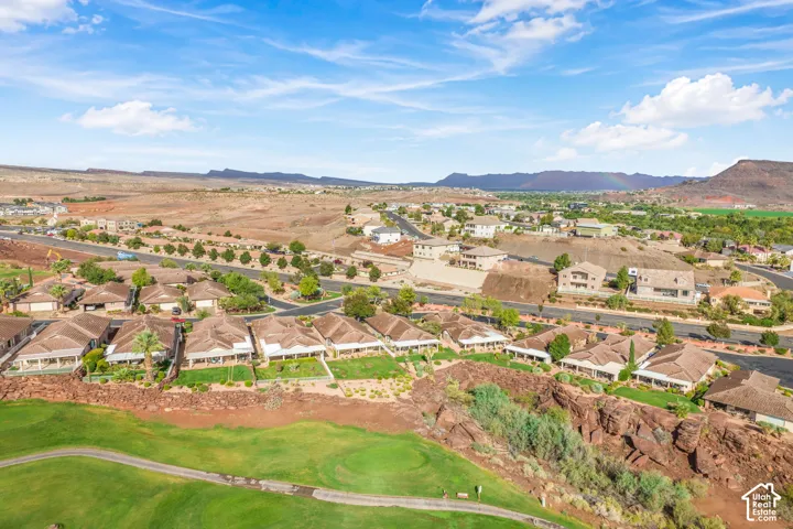 Aerial perspective featuring expansive desert terrain, golf course greens, and distant mountain backdrops
