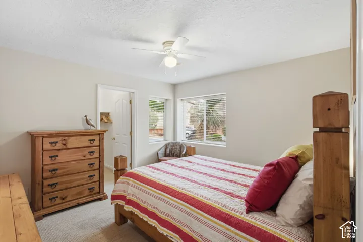 Room featuring neutral wall tones, multi-pane sliding windows, and a ceiling-mounted light fixture with fan blades