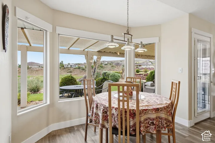 Bay window featuring wood-finish flooring, a multi-light brushed metal pendant fixture, and a glass-paneled exterior door