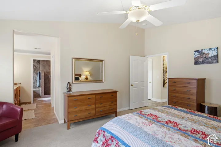 Vaulted ceiling featuring a central lighted ceiling fan, neutral wall tones, and interior doorways