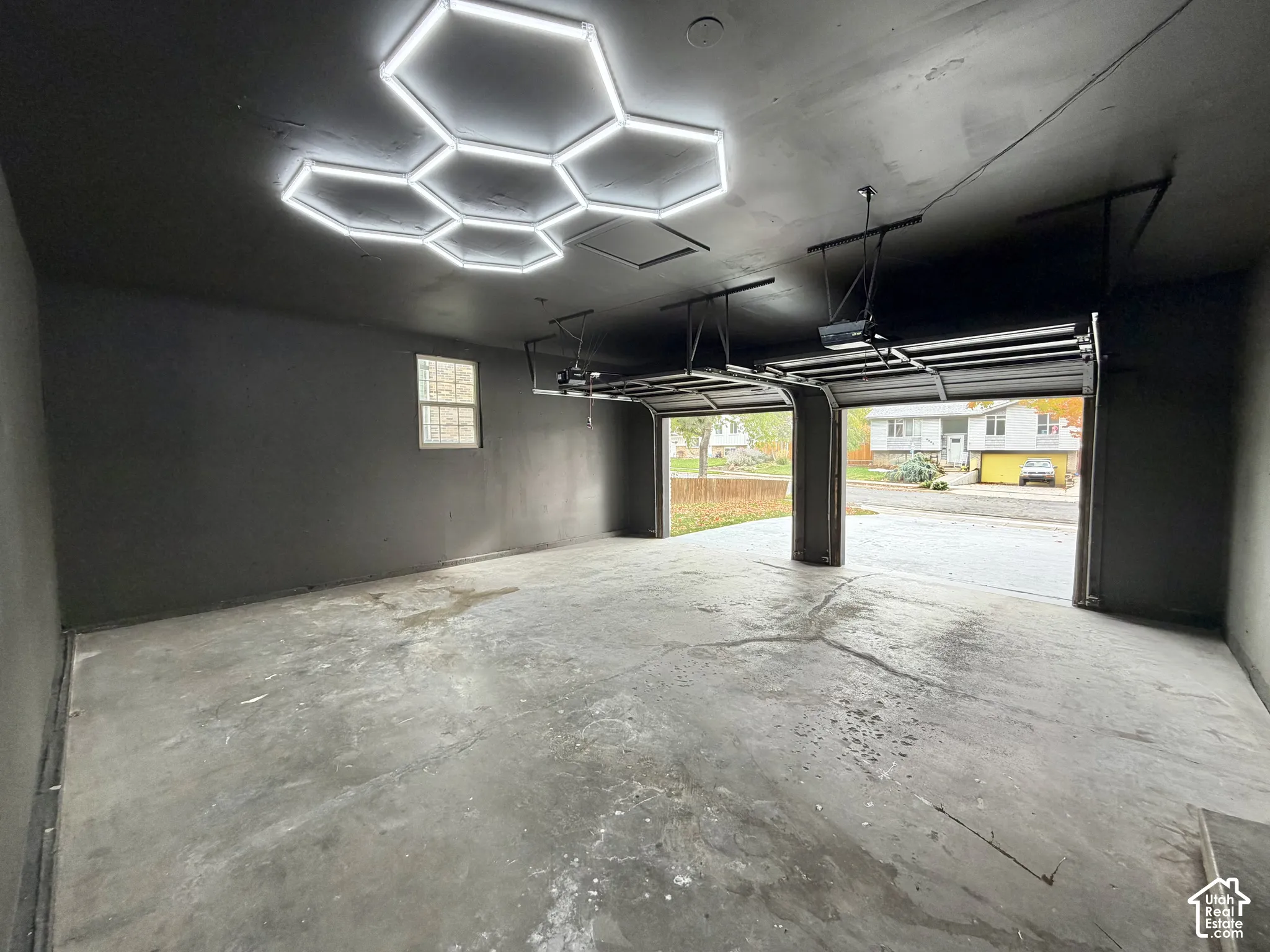 Two-car garage featuring finished walls, concrete flooring, and a multi-panel geometric LED ceiling fixture