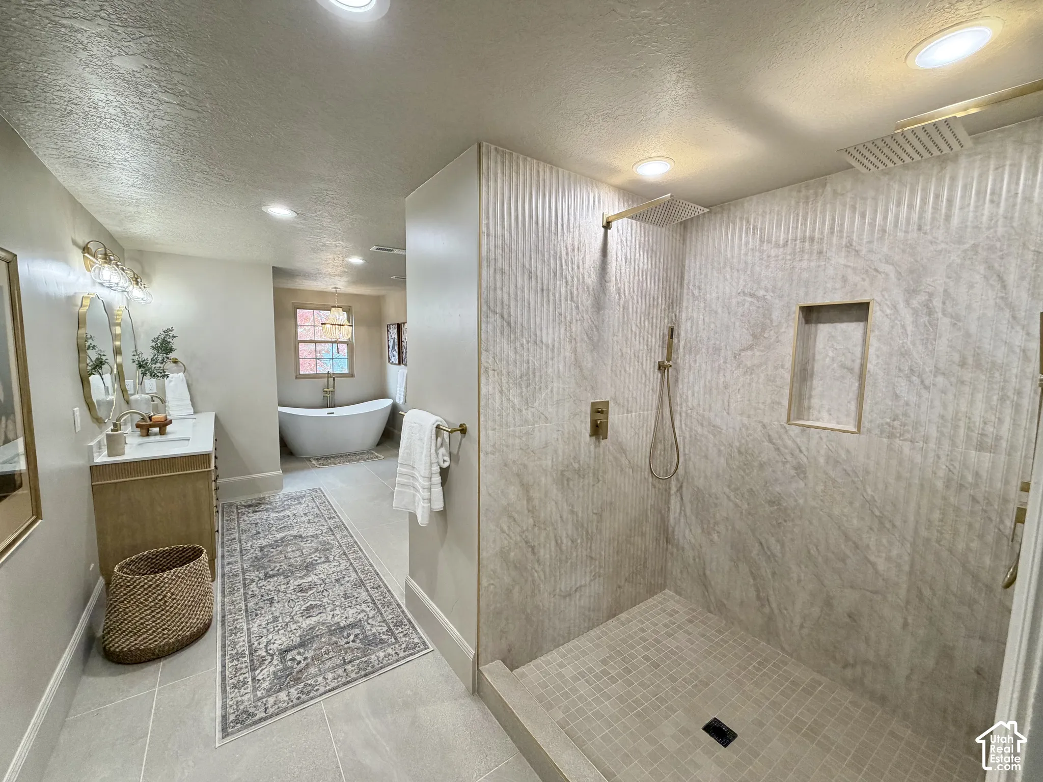 Walk-in shower featuring textured stone-finish tile surround, a built-in wall niche, and gold-tone fixtures including dual shower heads
