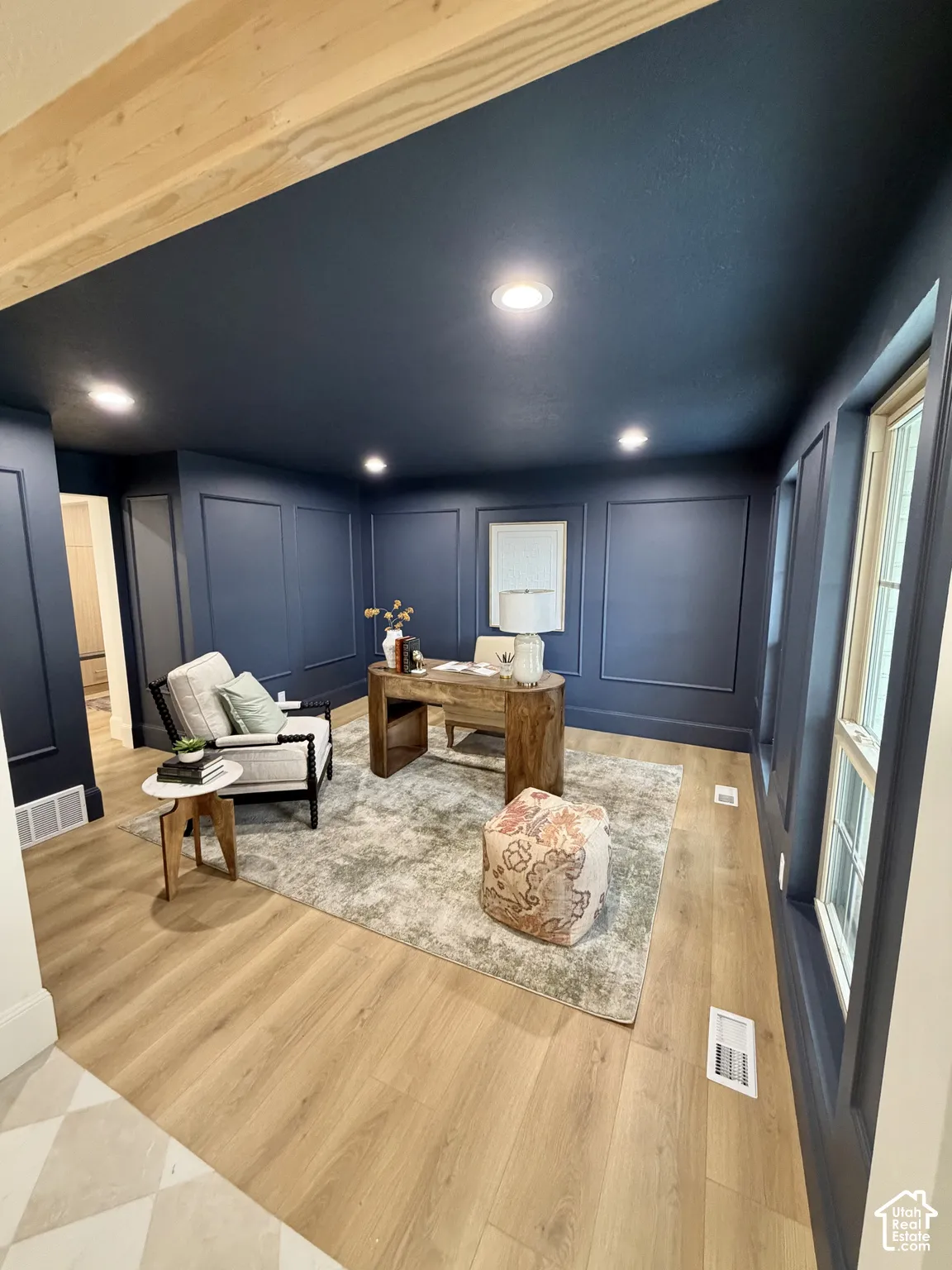 Deep blue wall panels featuring wainscoting detail, wood-finish flooring, recessed lighting, and exposed natural wood ceiling beams