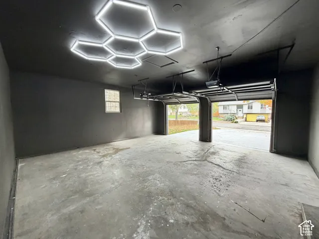 Two-car garage featuring finished walls, concrete flooring, and a multi-panel geometric LED ceiling fixture