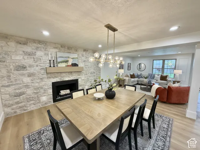 Floor-to-ceiling natural stone fireplace surround with integrated mantel, recessed lighting, wood-finish flooring, and multi-light chandelier