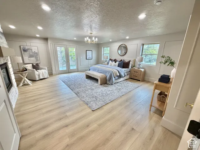 Wood-finish flooring, decorative wall molding, recessed lighting, stone-clad fireplace, and double-glass doors