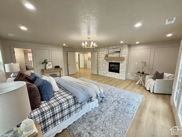Stone-faced fireplace with a natural wood mantel, recessed ceiling lighting, decorative wall paneling, and wood-finish flooring