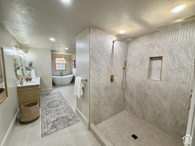 Walk-in shower featuring textured stone-finish tile surround, a built-in wall niche, and gold-tone fixtures including dual shower heads