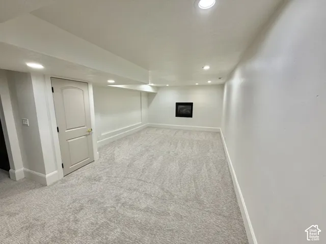 Neutral-toned interior space featuring recessed ceiling lighting, wall-to-wall carpeting, an inset wall-mounted fireplace, and a solid-core interior door