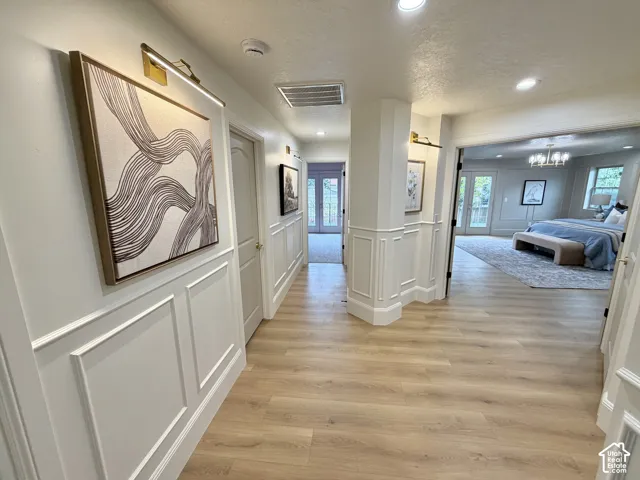 Interior hall featuring wood-finish flooring, wainscoting, recessed lighting, and wall-mounted light fixtures
