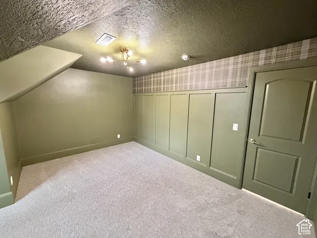 Interior room featuring wall-to-wall carpeting, wood paneling with decorative molding, plaid wallpaper accent, and a multi-arm modern light fixture