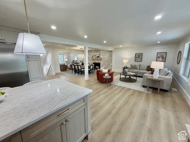 Kitchen featuring a stone-topped island with recessed-panel cabinetry, light wood-finish flooring, stone-faced fireplace, and wall molding