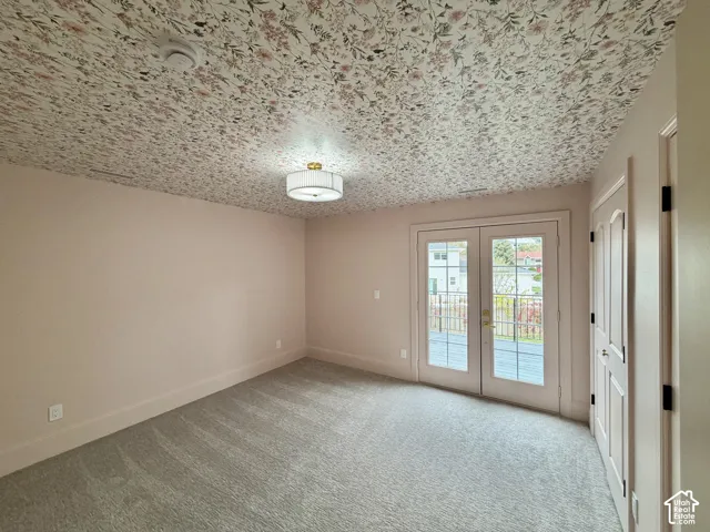 Floral-patterned ceiling treatment, neutral wall finish, carpeted flooring, drum-style flush-mount lighting, and glass-paned French doors