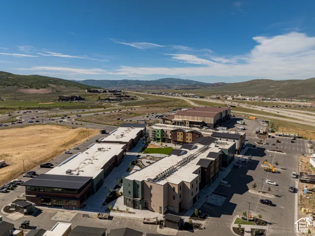 Aerial perspective of a multi-building complex featuring multi-story structures with flat roofs, brick and paneling exterior finishes, integrated parking areas, and landscaped courtyards with mountain scenery