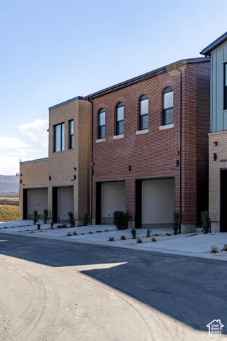 Multi-level exterior featuring red and tan brick masonry, arched window detailing, multi-car garage access, and concrete driveways