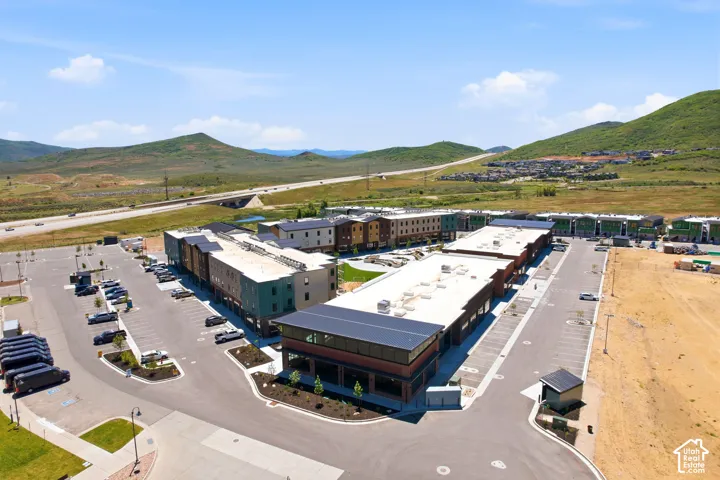 Aerial view featuring a multi-building complex, paved parking lots, integrated roadways, flat roofing systems, and a surrounding mountainous landscape