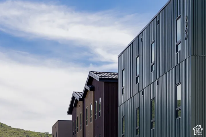 Contemporary multi-story exterior featuring vertical metal siding, peaked rooflines, and high-profile rectangular windows