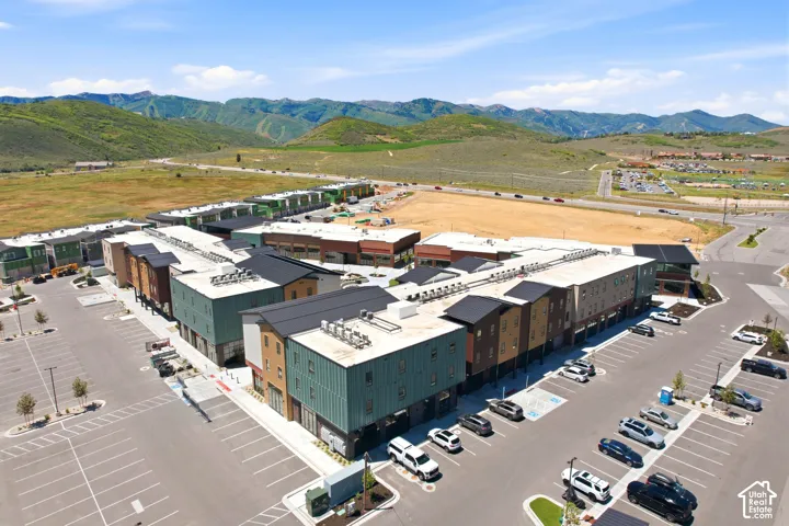 Multi-story residential complex featuring metal and composite siding, flat roof lines, paved surface parking, and a prominent mountain range backdrop