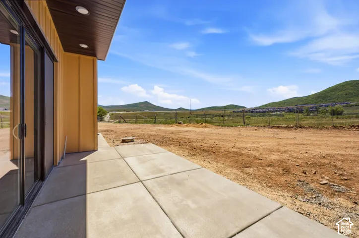 Concrete patio featuring recessed lighting, vertical board-and-batten siding, and mountainous terrain scenery