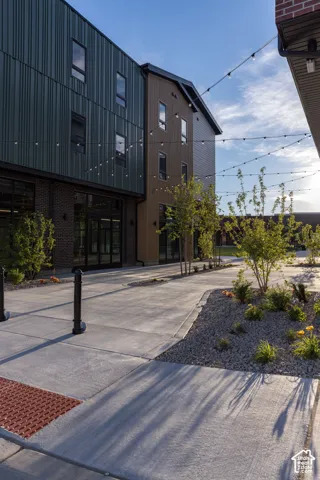 Multi-story structure featuring a combination of corrugated metal, wood-finish paneling, and brick masonry exterior siding, accented by large glass pane storefronts and overhead string lighting