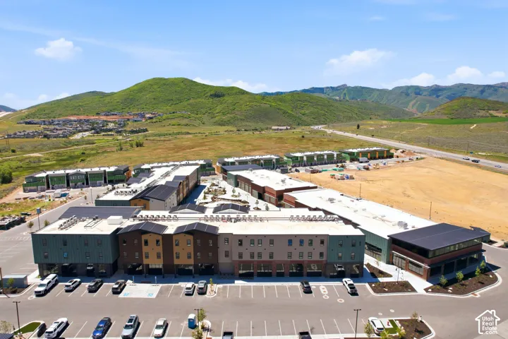 Aerial perspective of a multi-building complex featuring multi-story structures with varied exterior cladding, flat roof lines, and paved parking lots, set against a mountainous backdrop