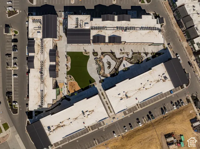 Aerial perspective featuring integrated parking areas, a central courtyard with artificial turf, landscaped rock garden elements, and complex roofing structures