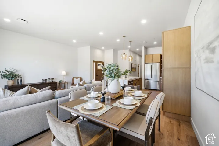 Open floor plan featuring wood-finish flooring, recessed lighting, tall built-in cabinetry, and pendant lighting over a kitchen island