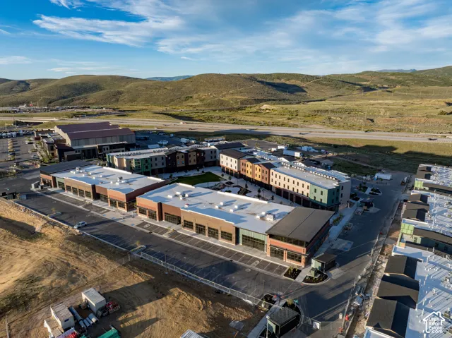 Aerial perspective of a multi-structure complex featuring modern masonry facades, flat roofing systems, expansive paved parking areas, and a landscaped central courtyard
