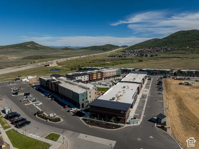 Aerial perspective of multi-level structures featuring flat roofing systems, mixed-material siding, surface-level parking, and mountain scenery
