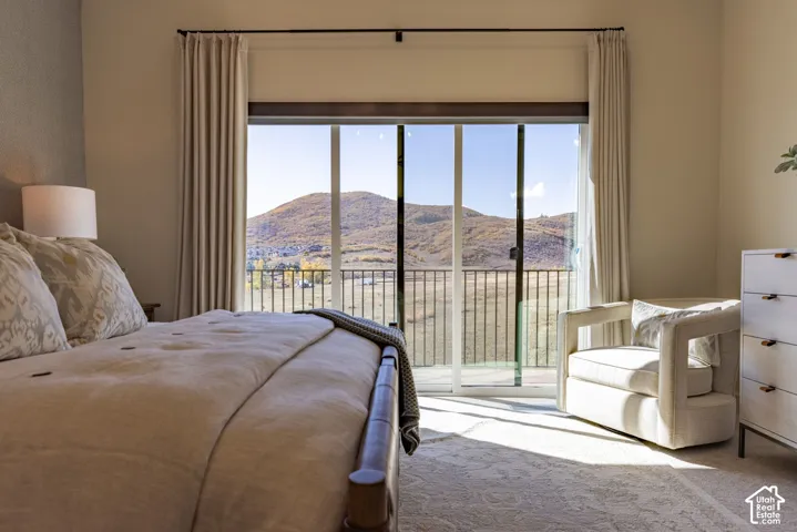 Floor-to-ceiling sliding glass door with a metal balcony railing, framing an expansive mountain landscape