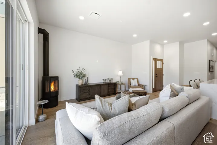 Freestanding black metal stove, wood-finish flooring, recessed lighting, and large glass sliding door
