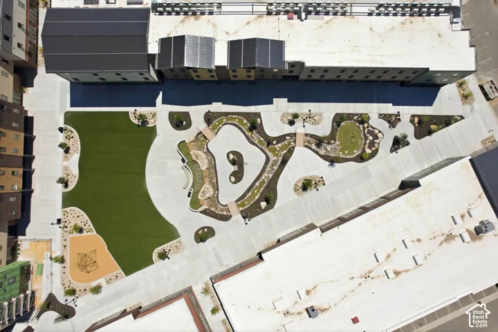 Aerial view of a courtyard featuring a central water feature with pedestrian bridges, manicured turf areas, xeriscaping with decorative rock, and a designated playground zone