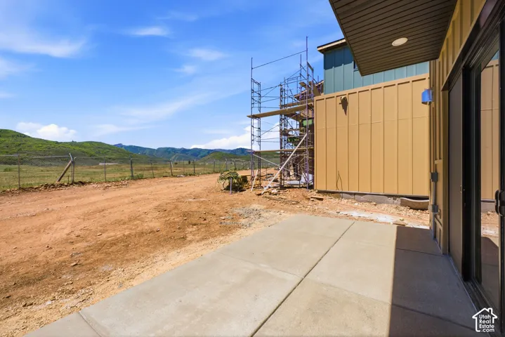 Concrete patio with a covered soffit, featuring vertical metal panel siding and mountain scenery