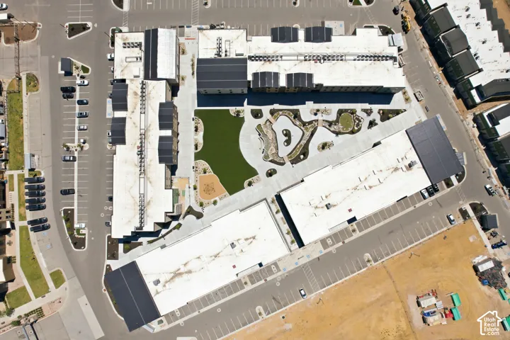 Aerial view of the complex featuring a central courtyard with a manicured lawn, paved walkways, landscaped garden beds, and dedicated surface parking