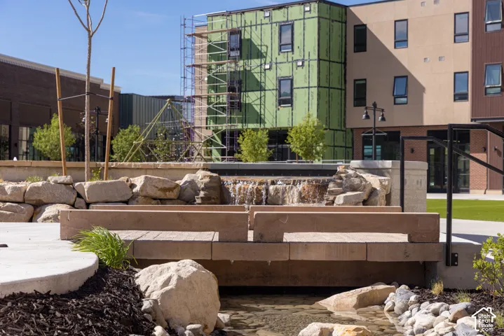 Stone-lined water feature with a stone bridge, rock landscaping, and concrete walkways